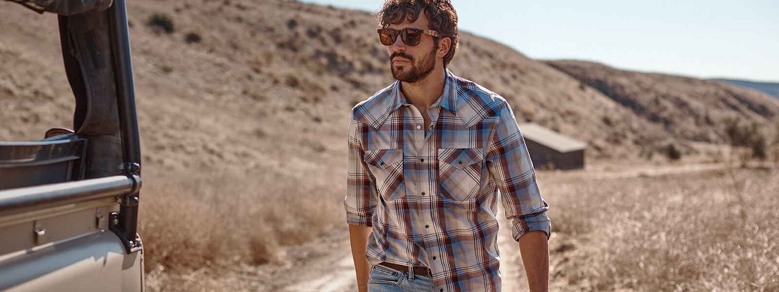 Man walking outside on sunny day wearing Pendleton plaid shirt