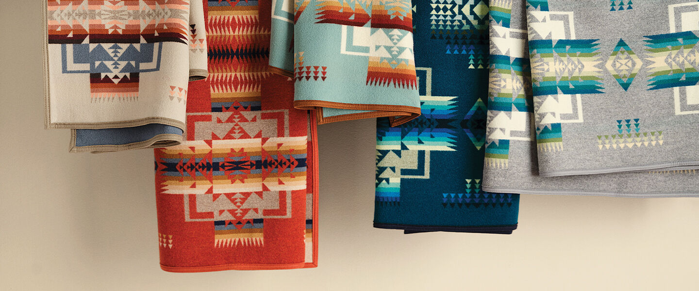 Multiple blankets hanging from a cord, with bright colors and patterns showcased