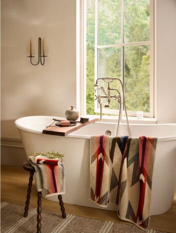 Throw blanket draped over a vintage wooden chair with a simple white wall as as background 