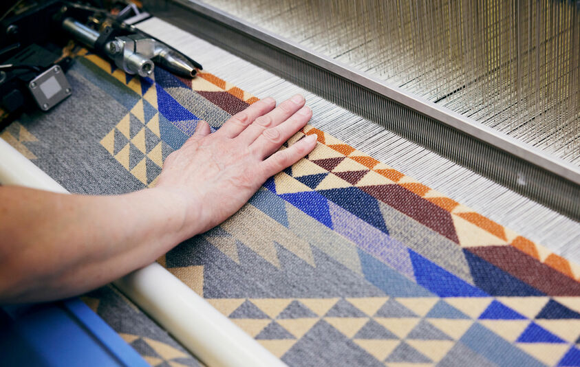 Iconic designs weaver working on wool machine