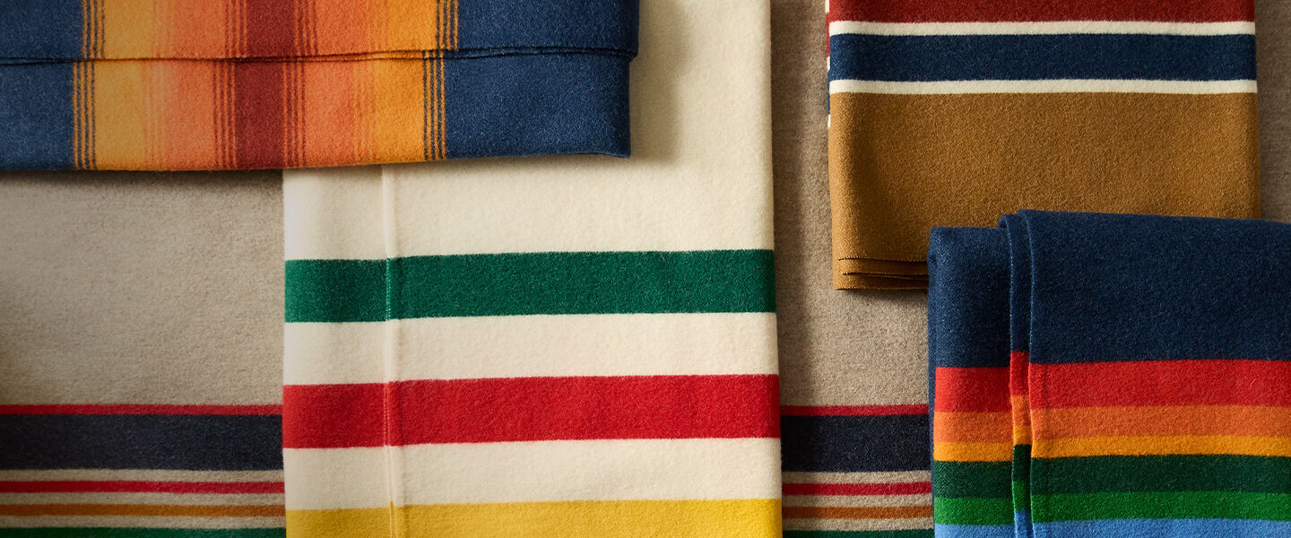 Top down view of multiple folded blankets with bold lines of color woven into each one.