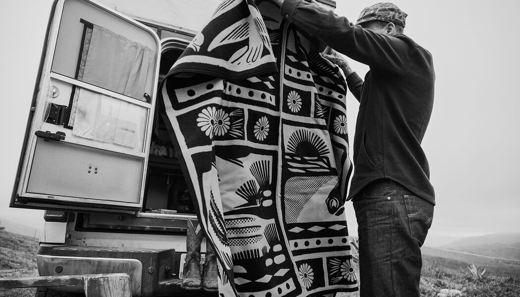 Black and white image of artist Jess Mudgett holding blanket