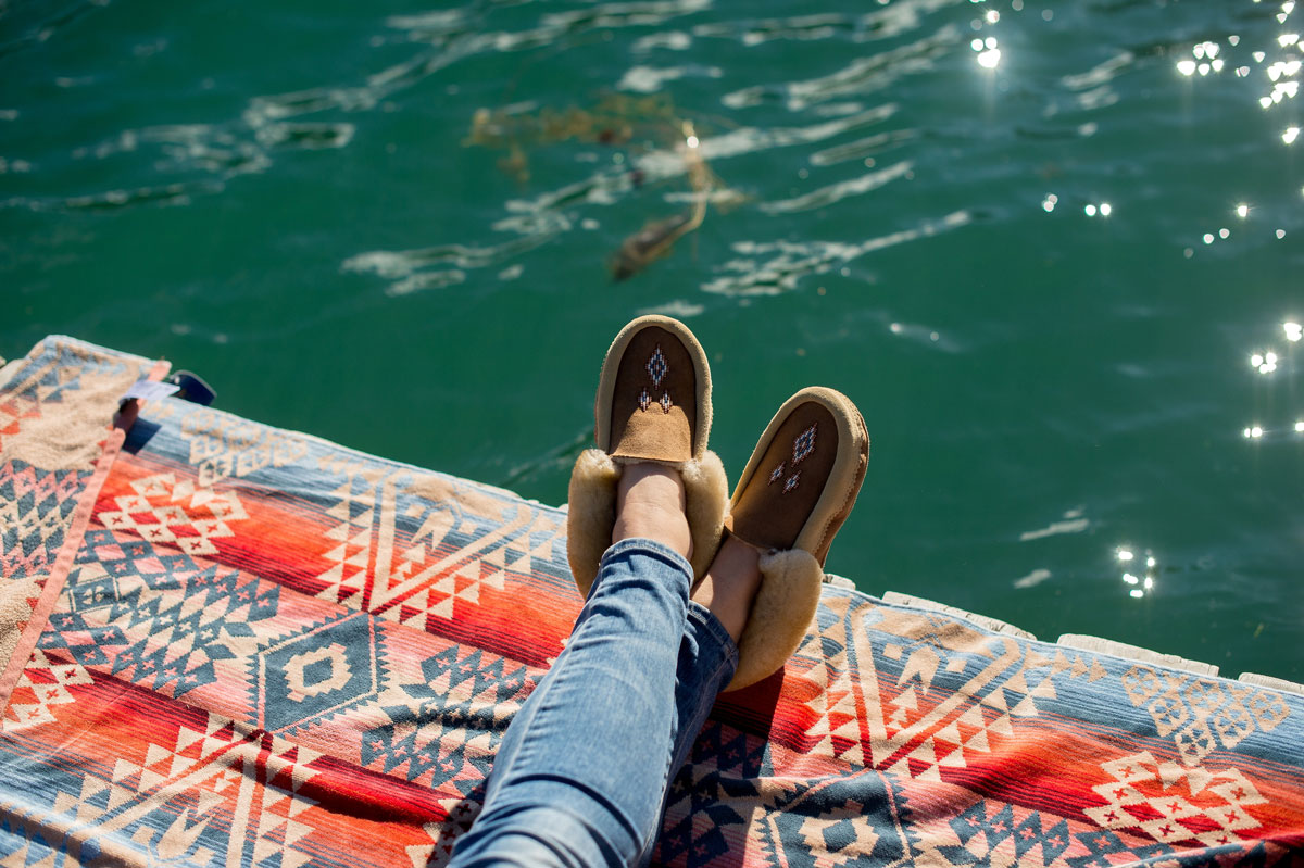 Photo by Rebecca Amber. Mocassined feet on a Pendleton Canyonlands towel by the water.