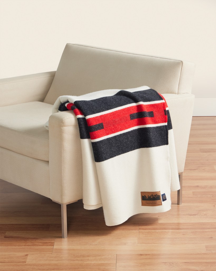 A white chair, with a Grand Teton National Park Blankety by Pendleton draped over it.