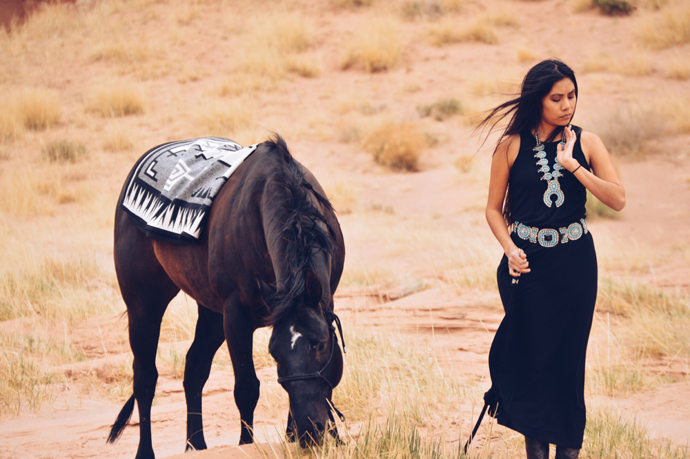 Shondina Lee Yikasbaa leads horse draped with Naskan saddle blanket