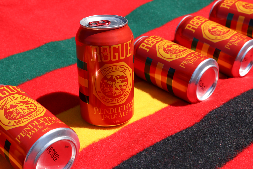 Five cans of Rogue IPA on a Rainier National Park blanket. 
