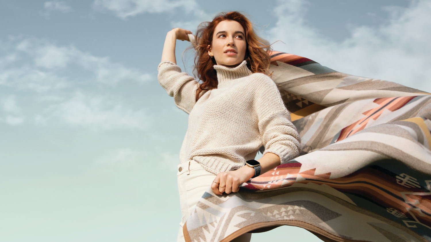 A young woman holds a Pendleton blanket wearing a Pendleton Fitbit device