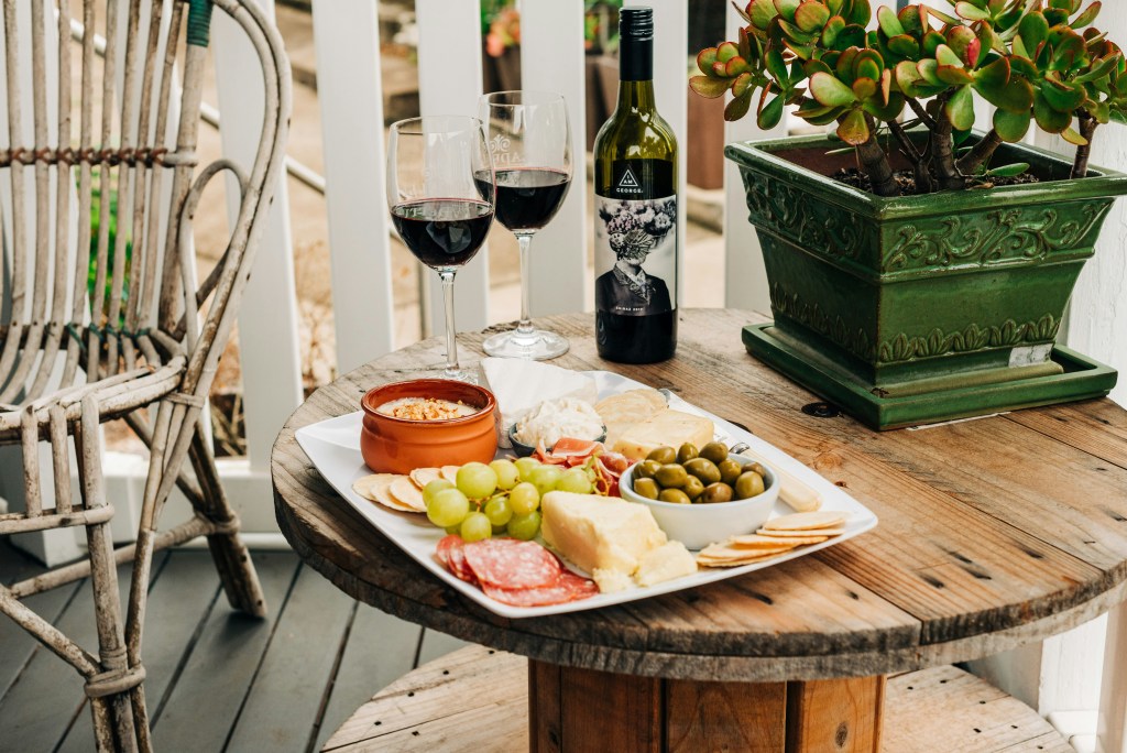 Porch view with small table and chair - meat and cheese tray and two glasses of wine are on the table.