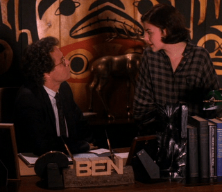 Audrey in a men's plaid shirt talks to an agent.