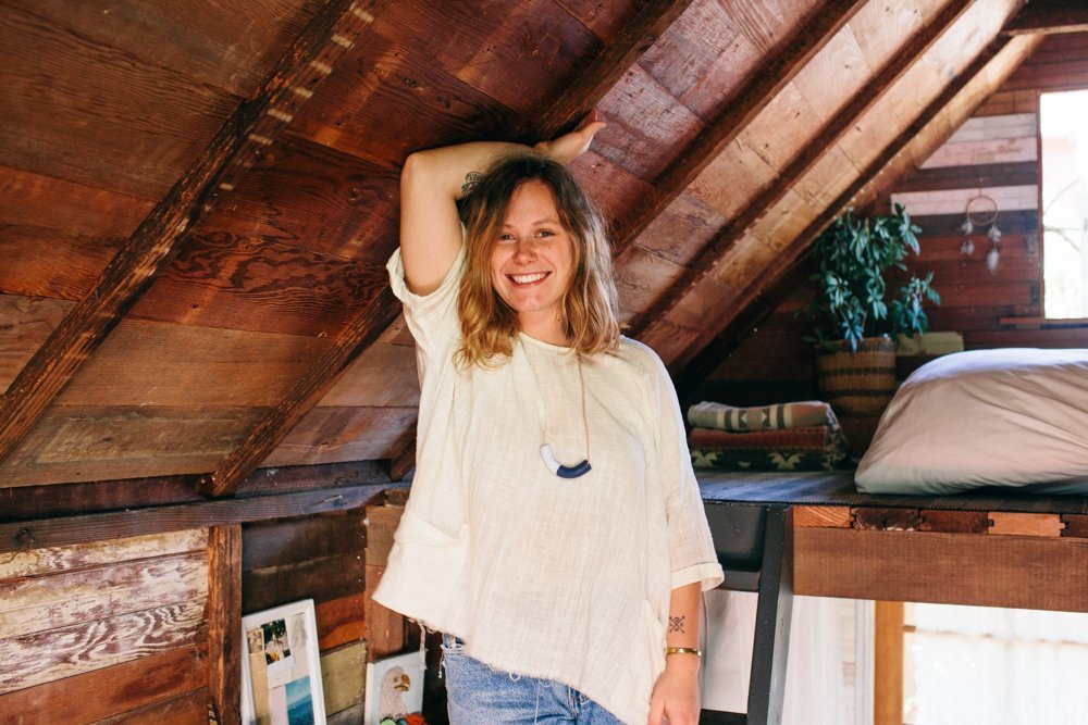 Woman standing on the ladder to her sleeping loft in a tiny home.