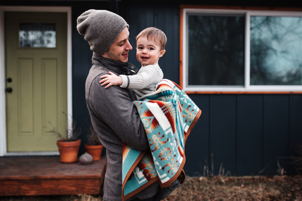 Grace_Adams_ photo of a young man holding a baby in a Pendleton blanket
