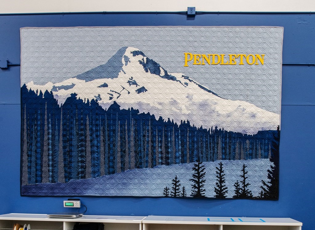 A banner that hangs in the Woolen Mill Store with mountain, lake, and trees.